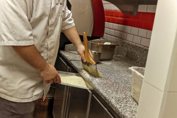 Unrecognizable chef man cleaning flour from kitchen after preparing food