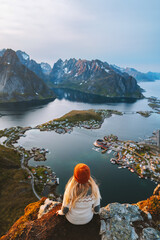 Woman tourist traveling in Norway hiking outdoor girl enjoying aerial view Lofoten islands, summer vacations solo traveler chilling on Reinebringen mountain cliff healthy lifestyle adventure trip