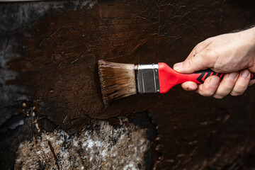 man applying primer with a brush to a damaged bitumen coating