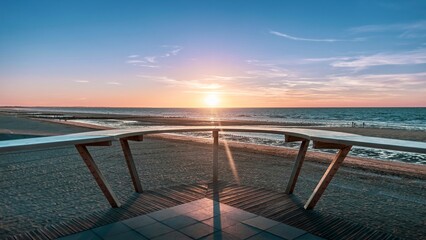 Sunrise over beach and ocean with benches on each side