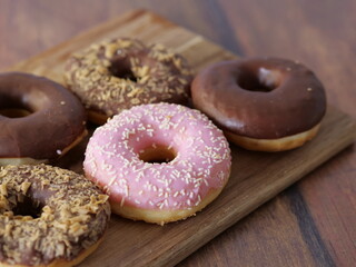 Wooden board with assorted donuts adorned with various toppings.