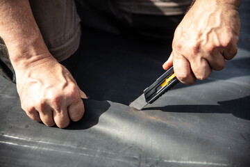 a craftsman cuts a rubber sheet apart with a cutter knife