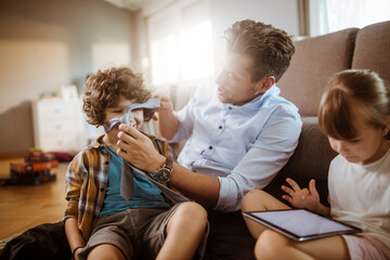 Happy father playing with son and daughter at home