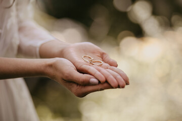 Close-up  of a woman delicately holding two wedding rings.