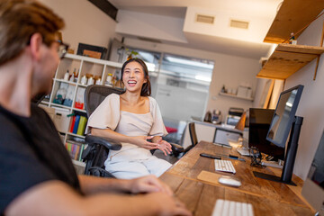 Asian woman and caucasian man sitting at a desk discussing ideas in a creative studio space
