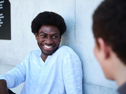 Man and woman sitting against a concrete wall having a conversation