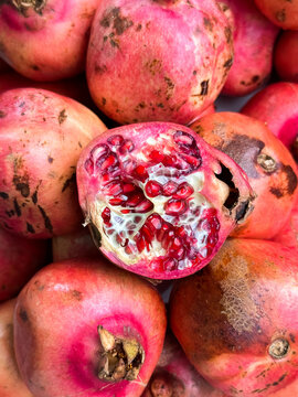 an open pomegranate on a pile of pomegranates