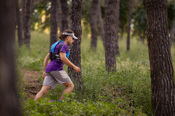 A man is running through a forest with a backpack on