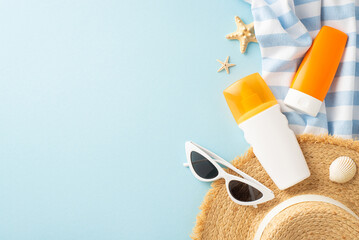 A creatively arranged beach scene featuring sunscreen bottles, a straw hat, sunglasses, and sea...