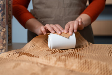 Close up of A woman wraps a product with eco-friendly honeycomb paper, highlighting the sustainable practices of a small business