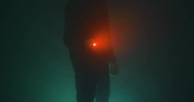 Silhouette of man with flashlight in the mist