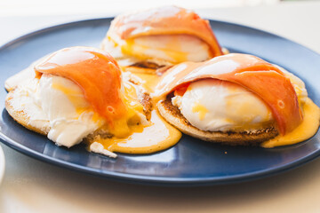 Toast with poached eggs, salmon and hollandaise sauce on a blue plate. Healthy breakfast concept