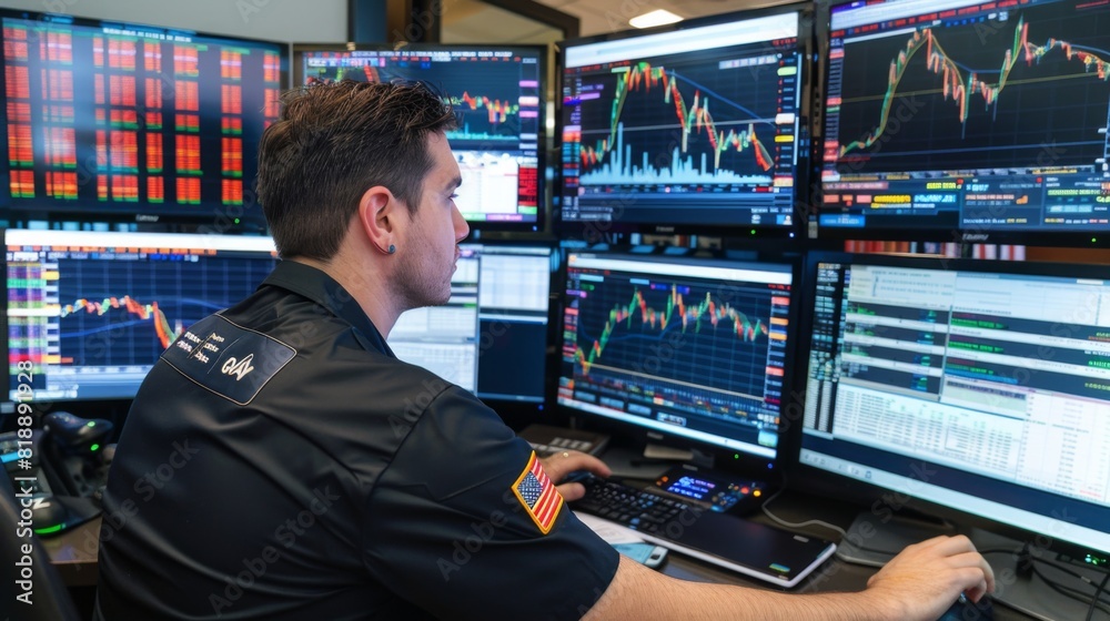 Poster trader monitoring financial graphs on multiple screens in a busy trading floor