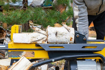 The elbow of the birch is instantly split by an electric wood splitter