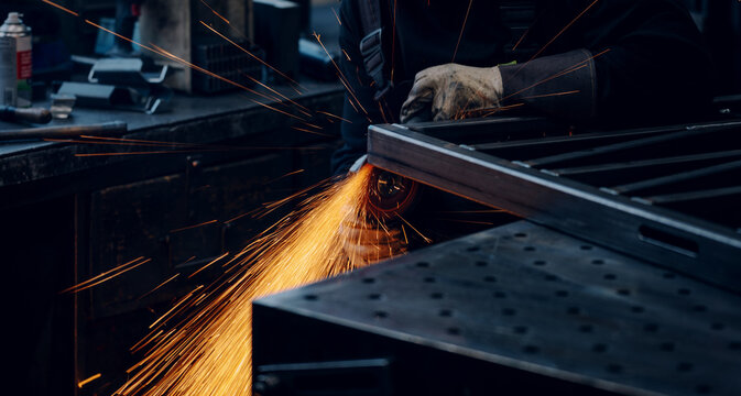 Hands of worker grinding a piece of metal
