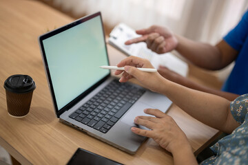 Two people are working on a laptop together, one of them pointing at the screen