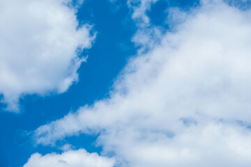 Obraz premium A stunning view of a clear blue sky dotted with fluffy white clouds, creating a serene and peaceful atmosphere. Vibrant uplifting sky - beauty and tranquility of a perfect sunny day.