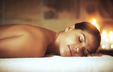 Woman, relax and zen in spa on massage bed for glow, wellness and cosmetics with candles....