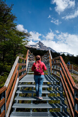 Mujer viajera con campera roja paseando por las pasarelas del Parque Nacional Los Glaciares, en El...