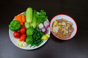 Meat, fried rice, green chillies, lemon, coriander leaves, badan, curd, carrot, cucumber, ginger, garlic, onion, tomato, bay leaves, kichmich, cardamom, cloves, cinnamon, jaitri, nutmeg are arranged o