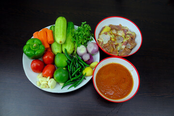 Meat, fried rice, green chillies, lemon, coriander leaves, badan, curd, carrot, cucumber, ginger, garlic, onion, tomato, bay leaves, kichmich, cardamom, cloves, cinnamon, jaitri, nutmeg are arranged o