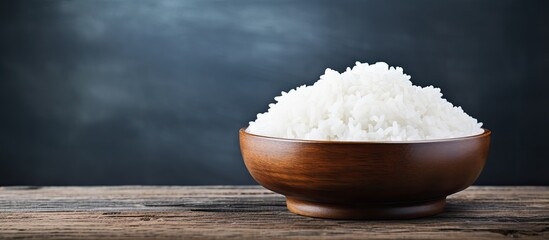 A copy space image of steamed white rice cooked in a wooden bowl on a rustic table