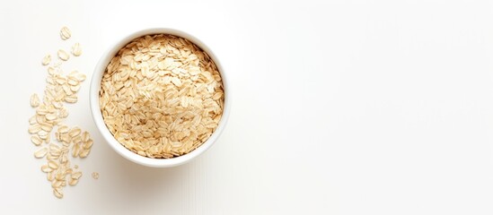 A top down view of a bowl containing rolled oats sits on a white table offering empty space for placing an image or text. Copyspace image