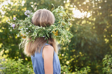 Girl in  Wreath Flowers on Head on Green Nature Sunset Background . Summer Middle Solstice...