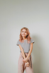 Fototapeta premium A 9-year-old girl stands against the wall, a child's portrait.