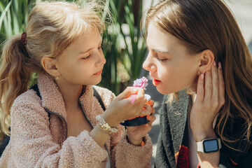 A little girl spoon-feeds sweets to her mother.