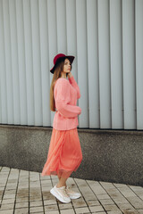 Beautiful woman in pink sweater and skirt, red hat.