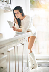 Woman, tablet and smile for online streaming, social media and networking by kitchen counter. Gen...