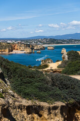 Ponta da Piedade near Lagos in Algarve, Portugal. Cliff rocks and tourist boat on sea. Praia Dona...