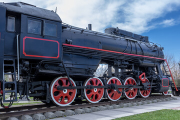 A black antique steam locomotive. The mainline passenger steam locomotive of the last century. Old railway transport. Transportation by rail.