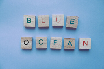 Phrase blue ocean made of wooden pieces on blue background. Business strategy concept. Market innovations idea. Text Blue Ocean on blue background with copy space. Creative business model. 