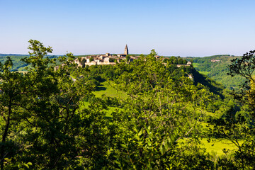Fototapeta premium Village médiéval de Puycelsi, au sommet de son plateau rocheux et protégé par ses remparts du XIVe siècle, dominant la Forêt de la Grésigne