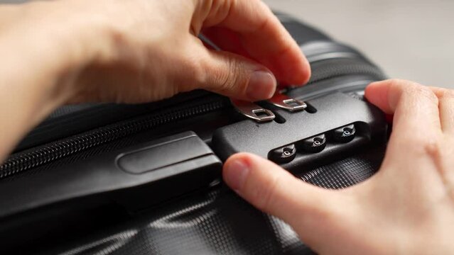 Close up hand close suitcase with combination lock. Hand entering code for open black suitcase