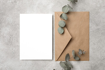 Blank invitation or greeting card mockup with envelope and eucalyptus twig, card mock up with copy...