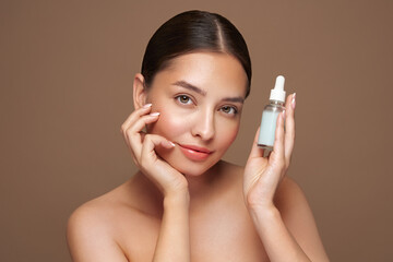 Beautiful elegant woman holding a cosmetic jar of oil serum or hyaluronic acid in her hand. Perfect...