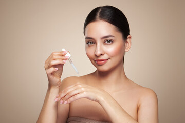 Young beautiful woman applying face serum with pipette. Cosmetic procedures for facial skin care