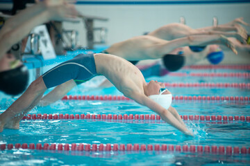 Boy swimmers start with backstroke swimming style in the pool