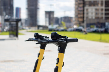 A yellow and black scooter with bicycle handlebar parked on the city road