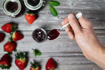 Man holding a teaspoon with strawberry jam. Delicious homemade strawberry jam, healthy breakfast.