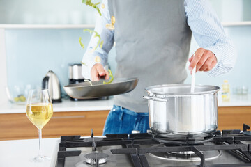 Man, pot and cooking in kitchen at house for healthy food, lunch and dinner with wine in glass. Chef, oven and frying pan in home for breakfast, eating and wellness with nutrition, protein and diet