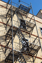 Fire escape hangs from brick buildings facade in city skyline