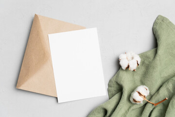 Fototapeta premium Invitation card mockup with envelope and cotton flowers decor, blank card with copy space, top view