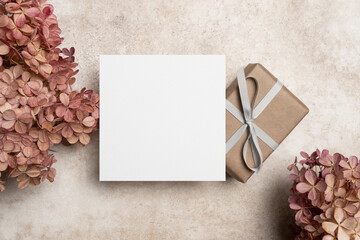 Blank square paper card mockup with gift box and dry hydrangea flowers decor, white card with copy...