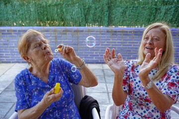 old mother and daughter playing with the bubbles. family having fun outside