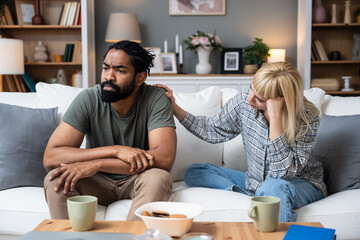 Communication problems, relationship difficulties. Young couple man and woman sitting on sofa at...