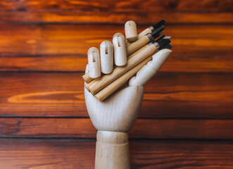 A artificial mannequin hand holds a set of linocut cutters on a wooden background. The concept of creativity and self-development of robots and artificial intelligence.